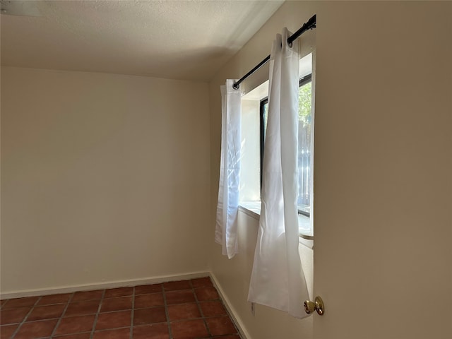 tiled spare room with a textured ceiling