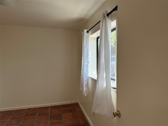 tiled spare room with a textured ceiling and baseboards