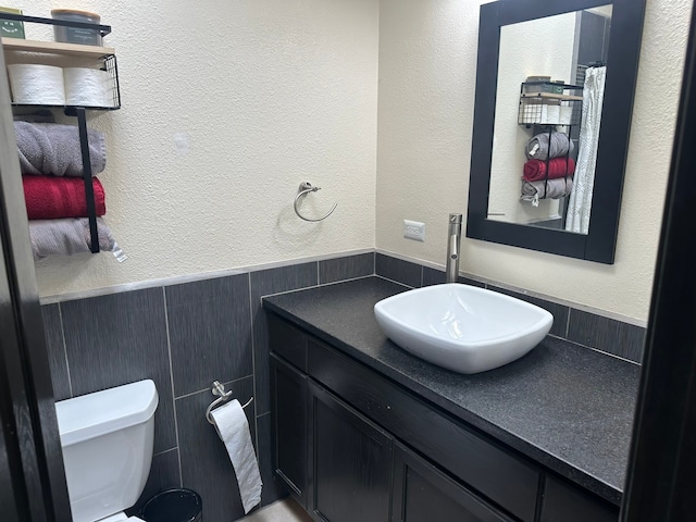 bathroom featuring tile walls, vanity, and toilet