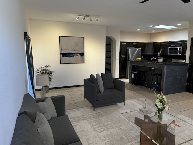 living room featuring a skylight, light tile patterned flooring, and sink