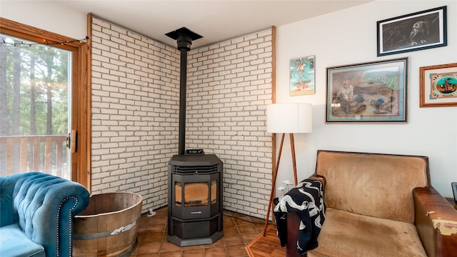 sitting room featuring tile patterned flooring, plenty of natural light, a wood stove, and brick wall