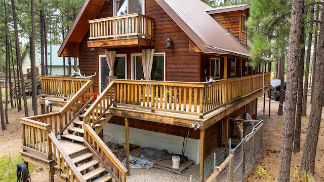 rear view of property featuring a balcony and a deck