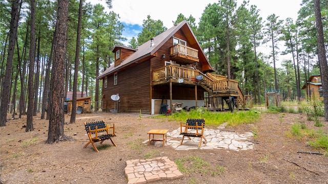 rear view of house featuring a balcony and a wooden deck