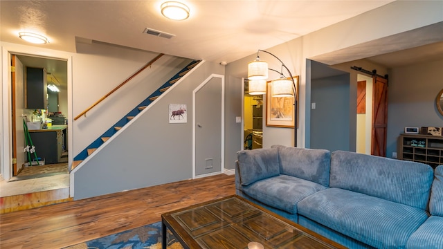 living room with a barn door and wood-type flooring