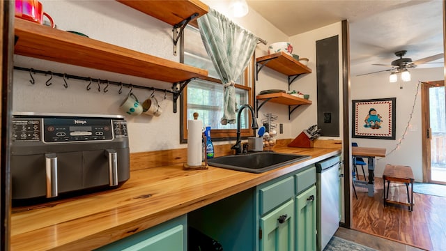 kitchen featuring stainless steel dishwasher, ceiling fan, sink, wood-type flooring, and green cabinets