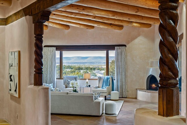 living room with wood ceiling, a mountain view, beamed ceiling, and a large fireplace