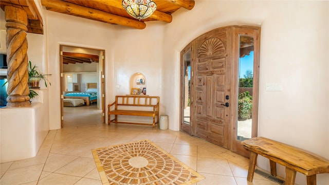 entryway featuring a wealth of natural light, light tile patterned floors, and beam ceiling