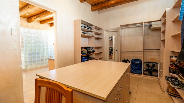 walk in closet with light tile patterned floors and beam ceiling