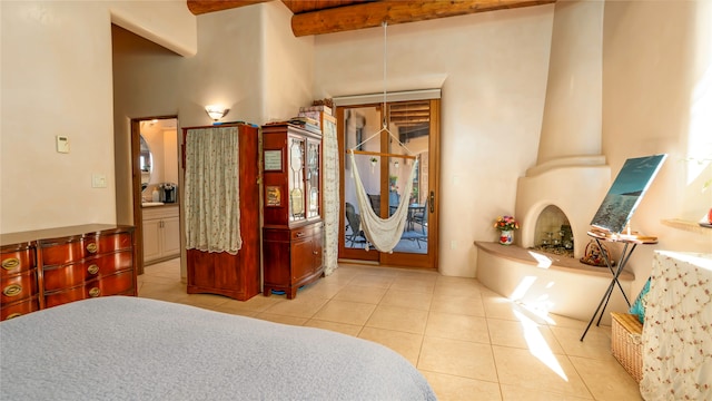 bedroom featuring a high ceiling, ornate columns, beam ceiling, and light tile patterned flooring