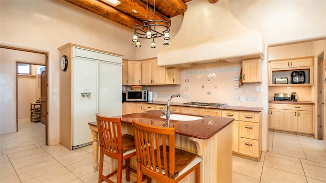 kitchen with an island with sink, a breakfast bar area, appliances with stainless steel finishes, and light brown cabinetry