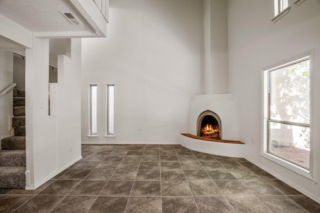 unfurnished living room with a wealth of natural light, visible vents, and a high ceiling