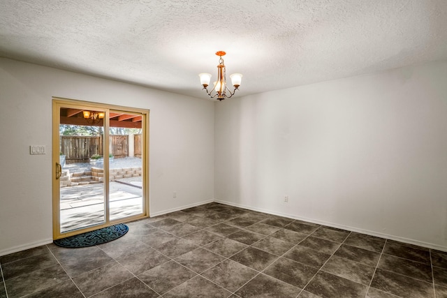 spare room with a notable chandelier, a textured ceiling, and baseboards