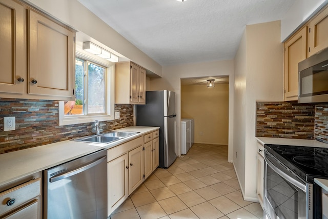 kitchen featuring a sink, washer / clothes dryer, appliances with stainless steel finishes, and light countertops