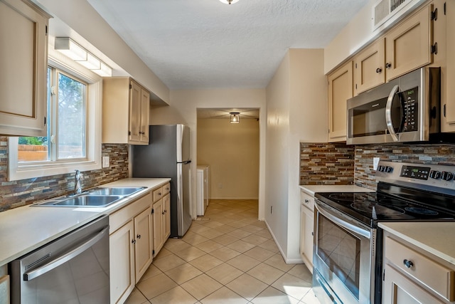 kitchen with light tile patterned floors, a sink, light countertops, appliances with stainless steel finishes, and a textured ceiling