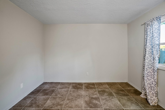 spare room with baseboards, dark tile patterned flooring, and a textured ceiling