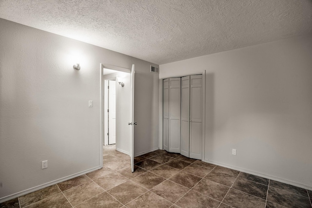 unfurnished bedroom featuring a closet, visible vents, a textured ceiling, and baseboards