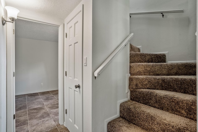 stairway featuring a textured ceiling