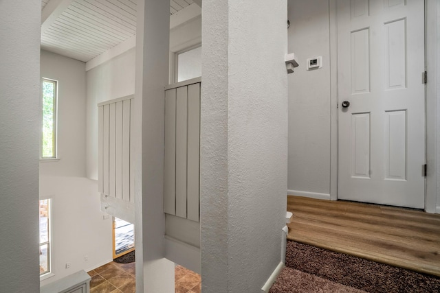 hallway featuring a textured wall and baseboards