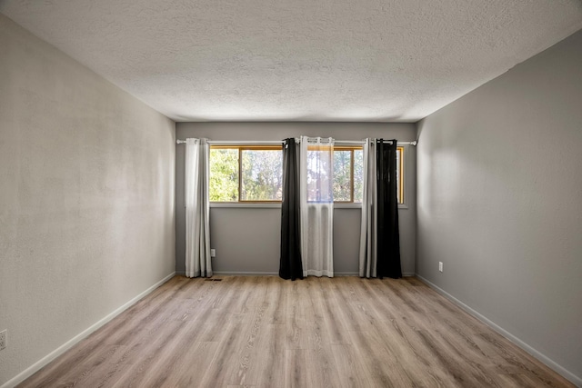 unfurnished room featuring light wood-style floors, baseboards, and a textured ceiling