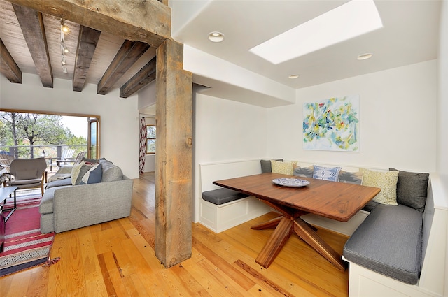 dining room featuring hardwood / wood-style flooring, a skylight, and beam ceiling