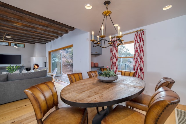 dining space with a chandelier, beam ceiling, and light hardwood / wood-style floors