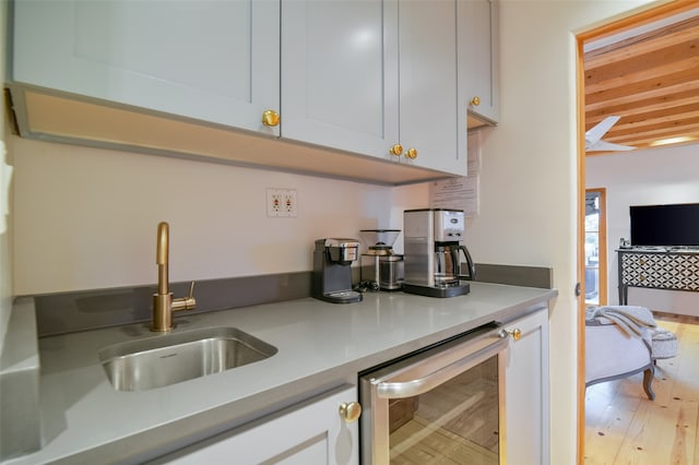 kitchen with light hardwood / wood-style flooring, wine cooler, and sink