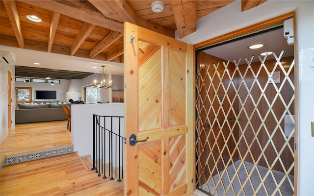 interior space featuring beamed ceiling, a wall unit AC, a chandelier, wood ceiling, and hardwood / wood-style flooring