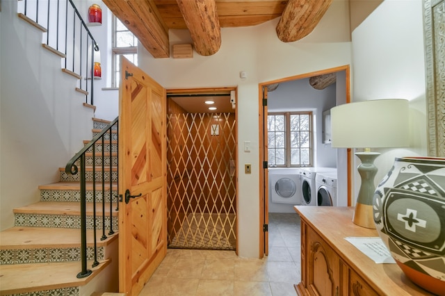 tiled foyer featuring washer and dryer, a healthy amount of sunlight, and beam ceiling