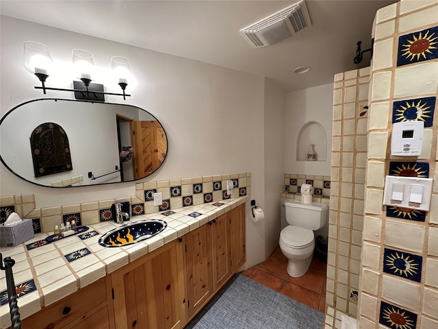 bathroom featuring vanity, tasteful backsplash, tile patterned flooring, toilet, and a shower