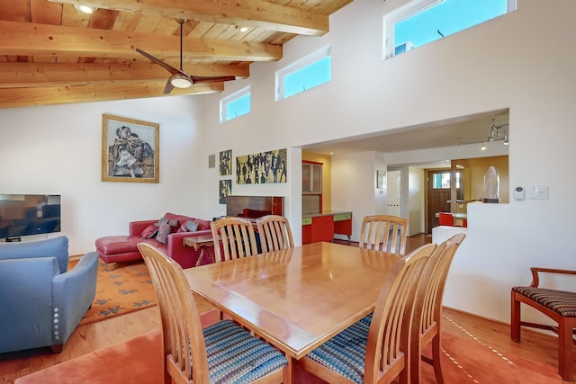 dining room featuring rail lighting, a tiled fireplace, wood finished floors, wooden ceiling, and beamed ceiling