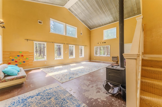 living room with concrete flooring, a wood stove, high vaulted ceiling, and a healthy amount of sunlight