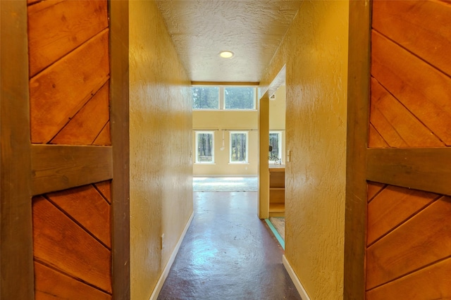 hall featuring a textured ceiling and concrete floors