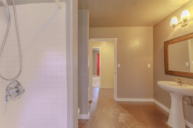 bathroom featuring a tile shower, concrete floors, a textured ceiling, and sink