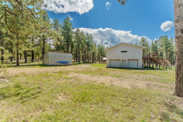 view of yard with an outbuilding, a garage, and a wooden deck