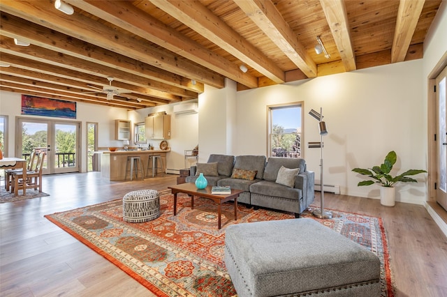 living room with a wall unit AC, french doors, beam ceiling, track lighting, and light hardwood / wood-style floors