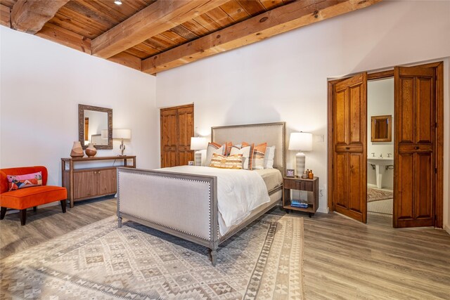 bedroom with sink, hardwood / wood-style floors, wooden ceiling, and beam ceiling