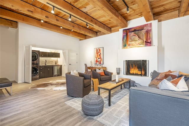 living room with wine cooler, stacked washer / drying machine, wood ceiling, light wood-type flooring, and a large fireplace