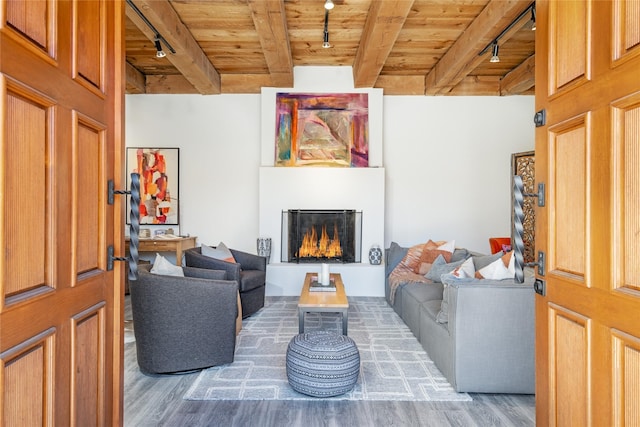 living room featuring rail lighting, hardwood / wood-style floors, wooden ceiling, and beam ceiling