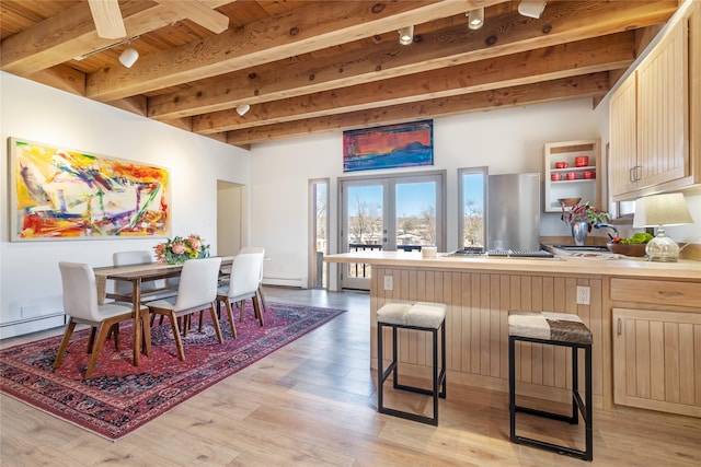 dining area featuring beam ceiling, a baseboard radiator, light hardwood / wood-style floors, and french doors