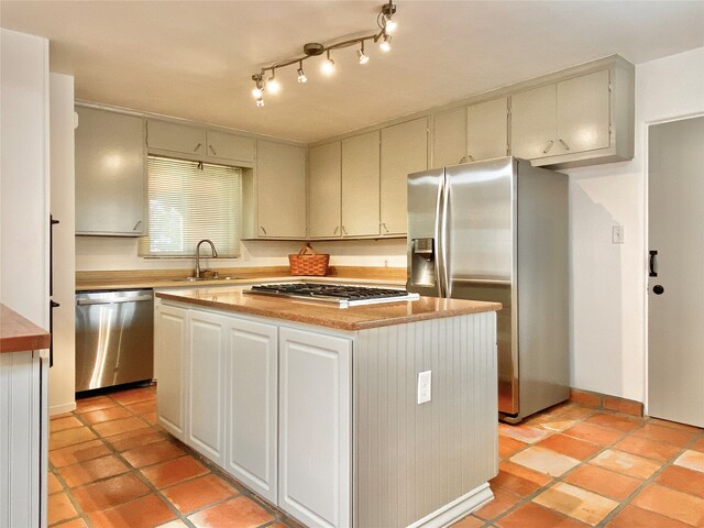 kitchen featuring a kitchen island, light tile patterned flooring, sink, and appliances with stainless steel finishes