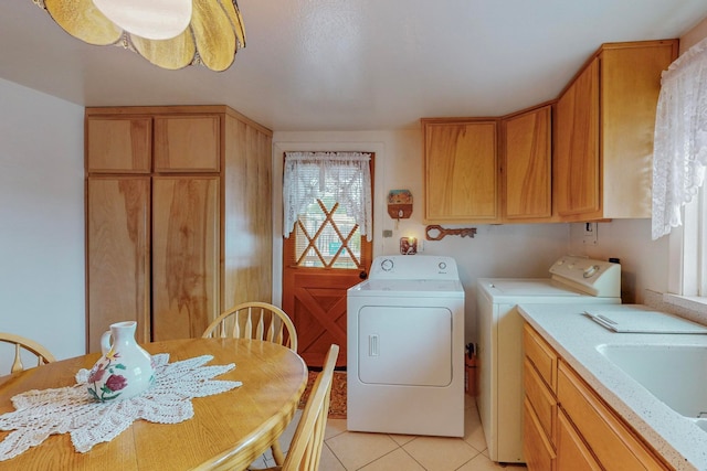 laundry area featuring light tile patterned floors, washing machine and clothes dryer, and cabinets