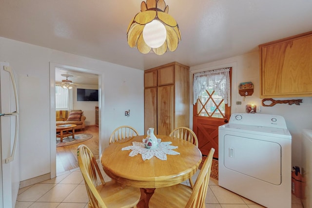 tiled dining area with ceiling fan and washer / dryer