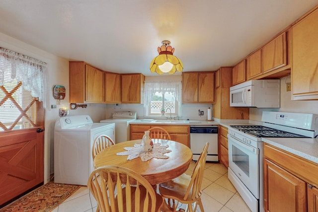 kitchen featuring white appliances, light tile patterned flooring, sink, and washing machine and clothes dryer