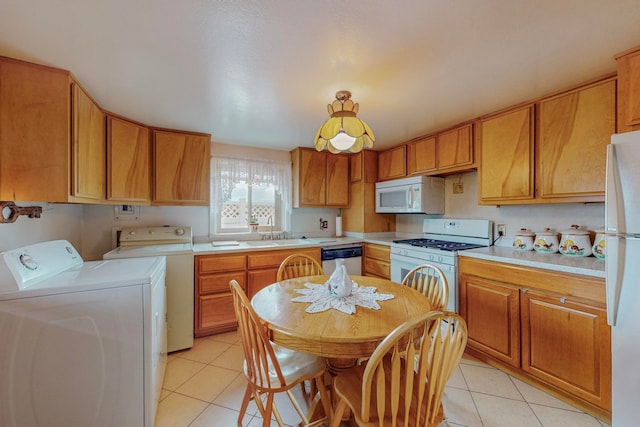 kitchen with washer and clothes dryer, light tile patterned flooring, sink, and white appliances