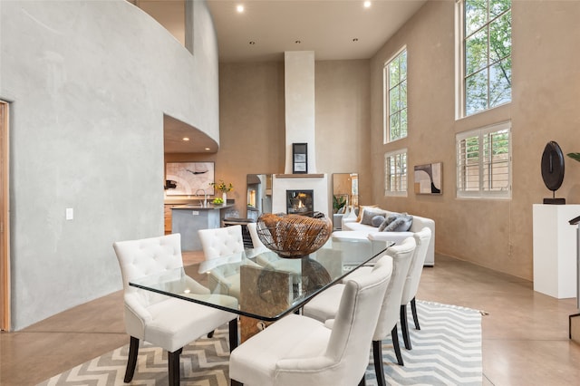 dining space featuring a fireplace, a towering ceiling, and sink