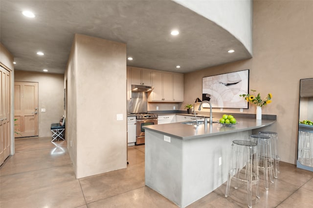 kitchen with stainless steel stove, kitchen peninsula, a breakfast bar area, and sink