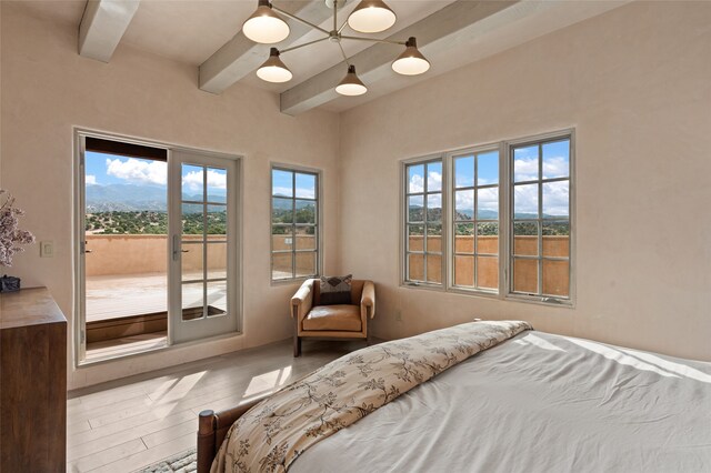 bedroom with access to exterior, hardwood / wood-style flooring, beam ceiling, and multiple windows