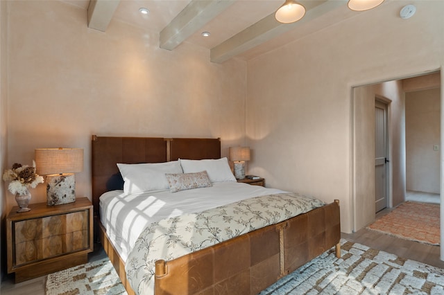 bedroom with beamed ceiling and light wood-type flooring