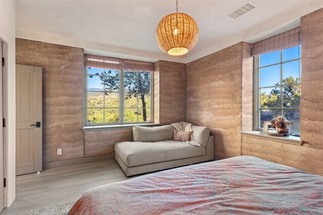 bedroom with multiple windows and light hardwood / wood-style flooring