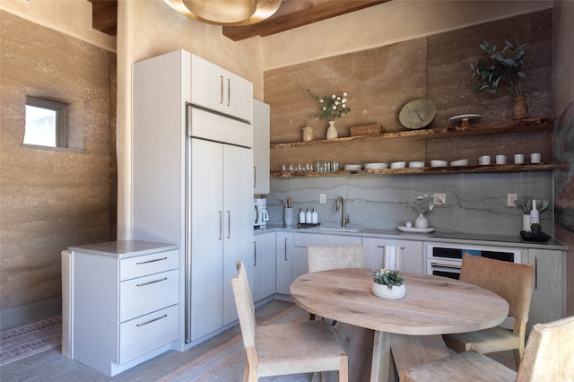 kitchen featuring decorative backsplash, sink, light hardwood / wood-style flooring, and white cabinets